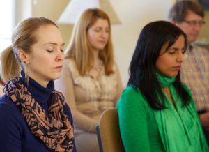 Group of people sitting with eyes closed, meditating at a TM Center